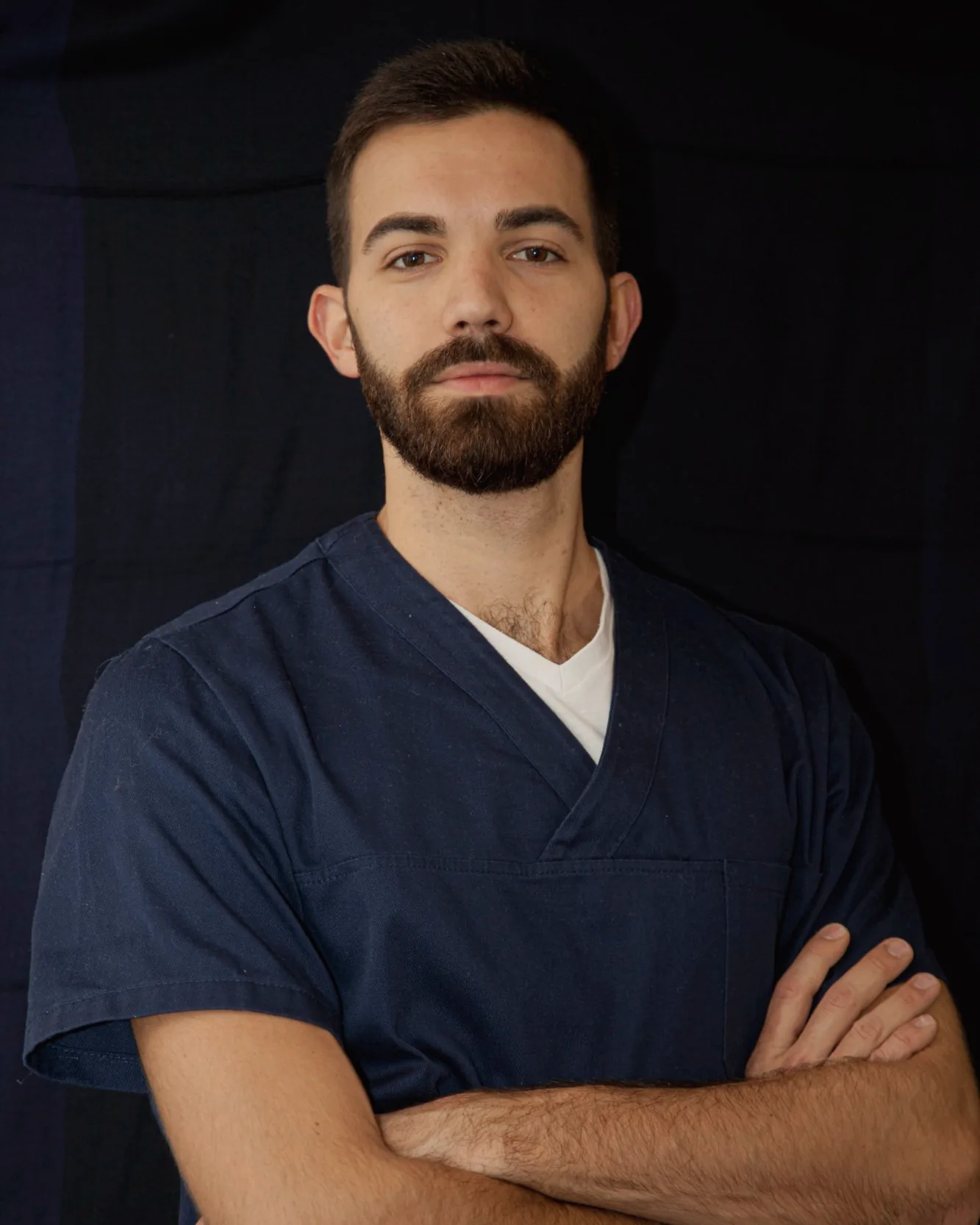 Ritratto di Alessandro Giovannini, osteopata, a braccia conserte su fondo scuro